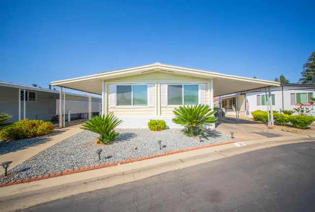 a front view of a house with a yard and potted plants