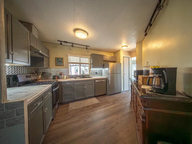 a kitchen with stainless steel appliances granite countertop a sink stove and refrigerator