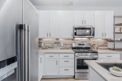 a kitchen with white cabinets and appliances
