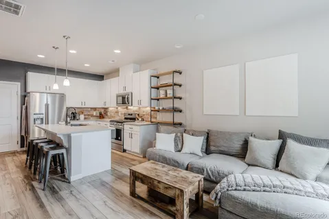 a living room with stainless steel appliances furniture and a kitchen view