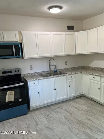 a kitchen with granite countertop white cabinets and stainless steel appliances