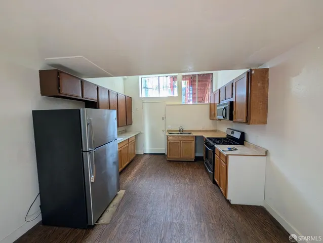 a kitchen with a refrigerator a stove top oven a counter space and wooden floor