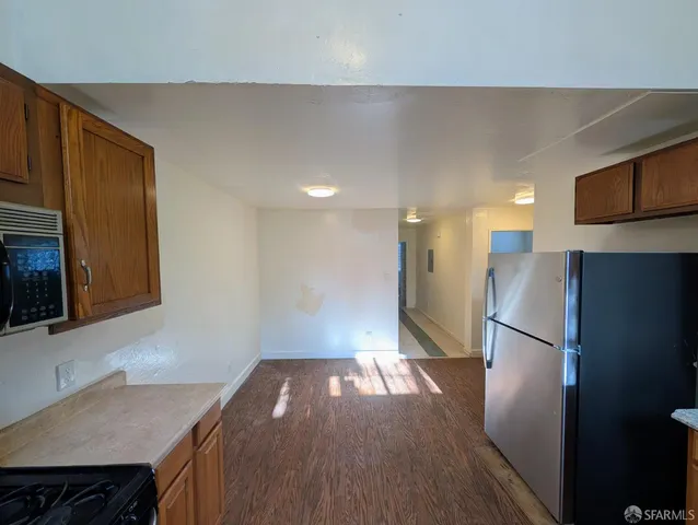a view of kitchen with stainless steel appliances kitchen island wooden floor and cabinets