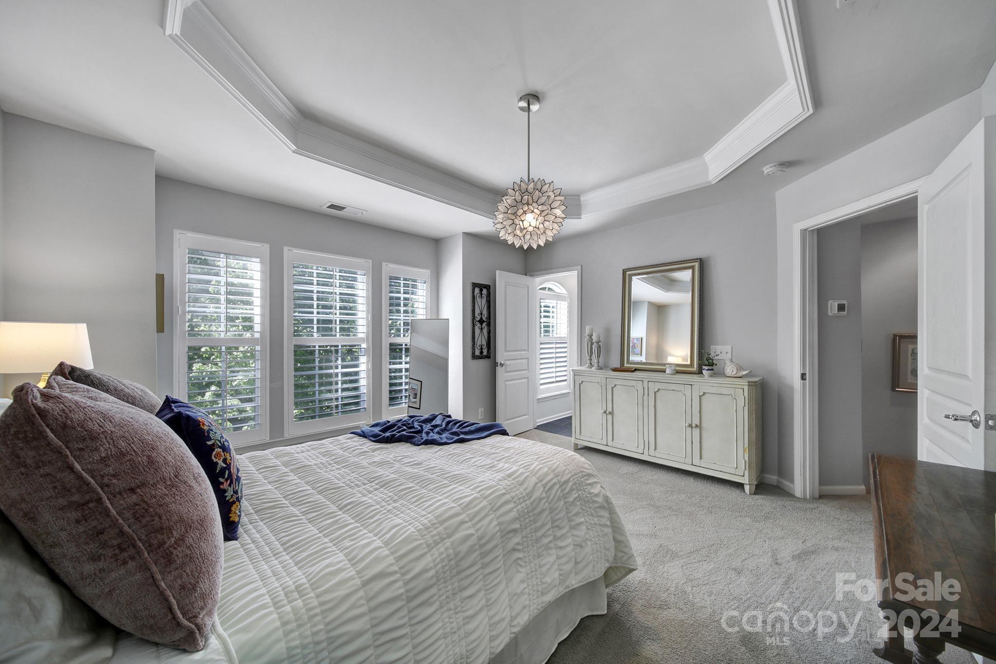 726 Passage Drive Fort Mill, SC 29708 - Photo 20 of 43 a spacious bedroom with a large bed a chandelier and windows