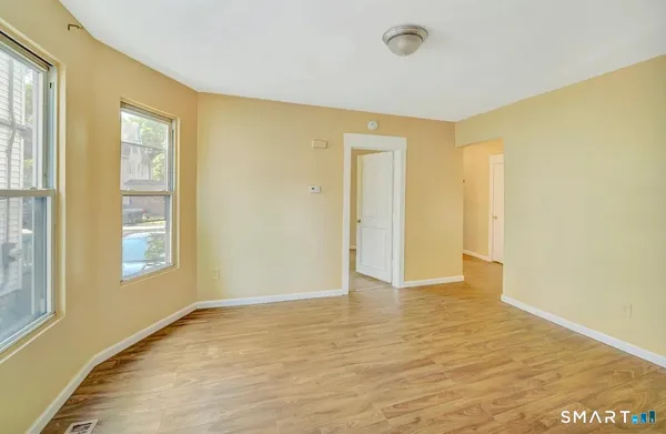 a view of an empty room with window and wooden floor