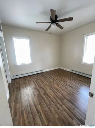 an empty room with wooden floor fan and windows