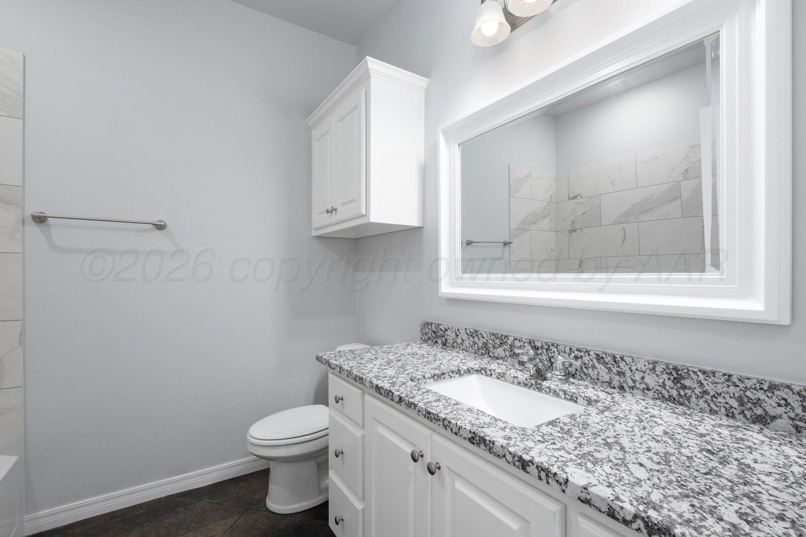 10311 Ruse Street Amarillo, TX 79118 - Photo 23 of 29 a bathroom with a granite countertop sink a toilet and a mirror