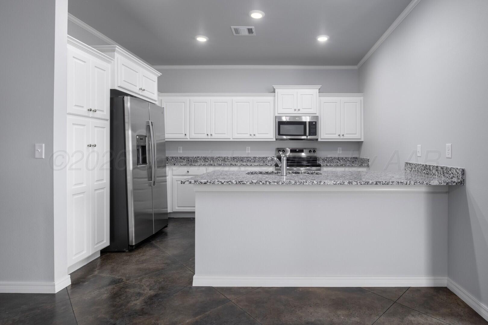 10311 Ruse Street Amarillo, TX 79118 - Photo 9 of 29 a kitchen with kitchen island granite countertop a stove a sink and a refrigerator