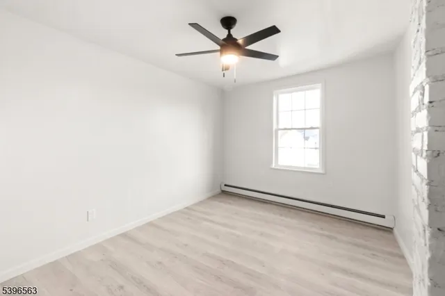 an empty room with a window and a ceiling fan