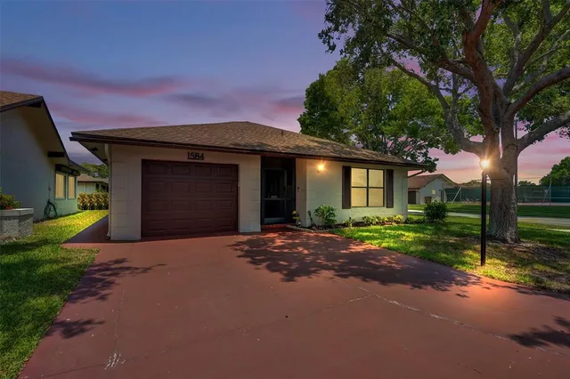 a front view of a house with a garden and trees