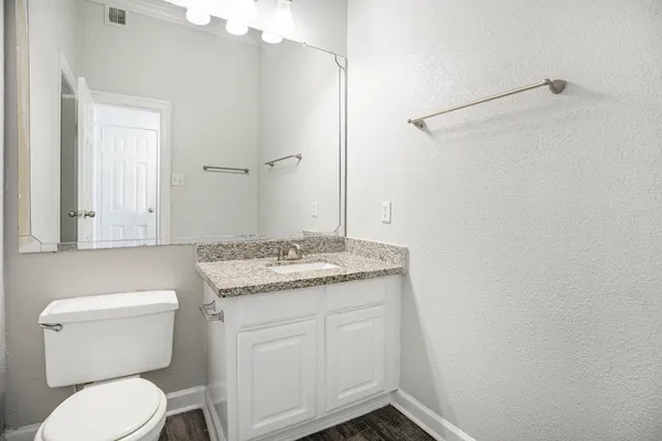 a bathroom with a granite countertop toilet and a sink