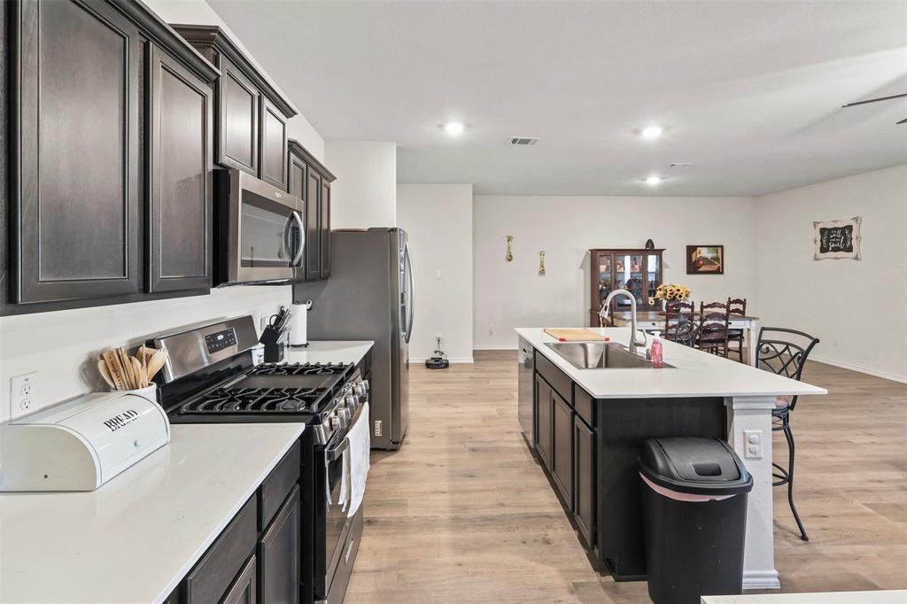 742 Buttercup Drive Pilot Point, TX 76258 - Photo 8 of 20 Kitchen featuring stainless steel appliances, light wood-style flooring, a breakfast bar, an island with sink, and recessed lighting