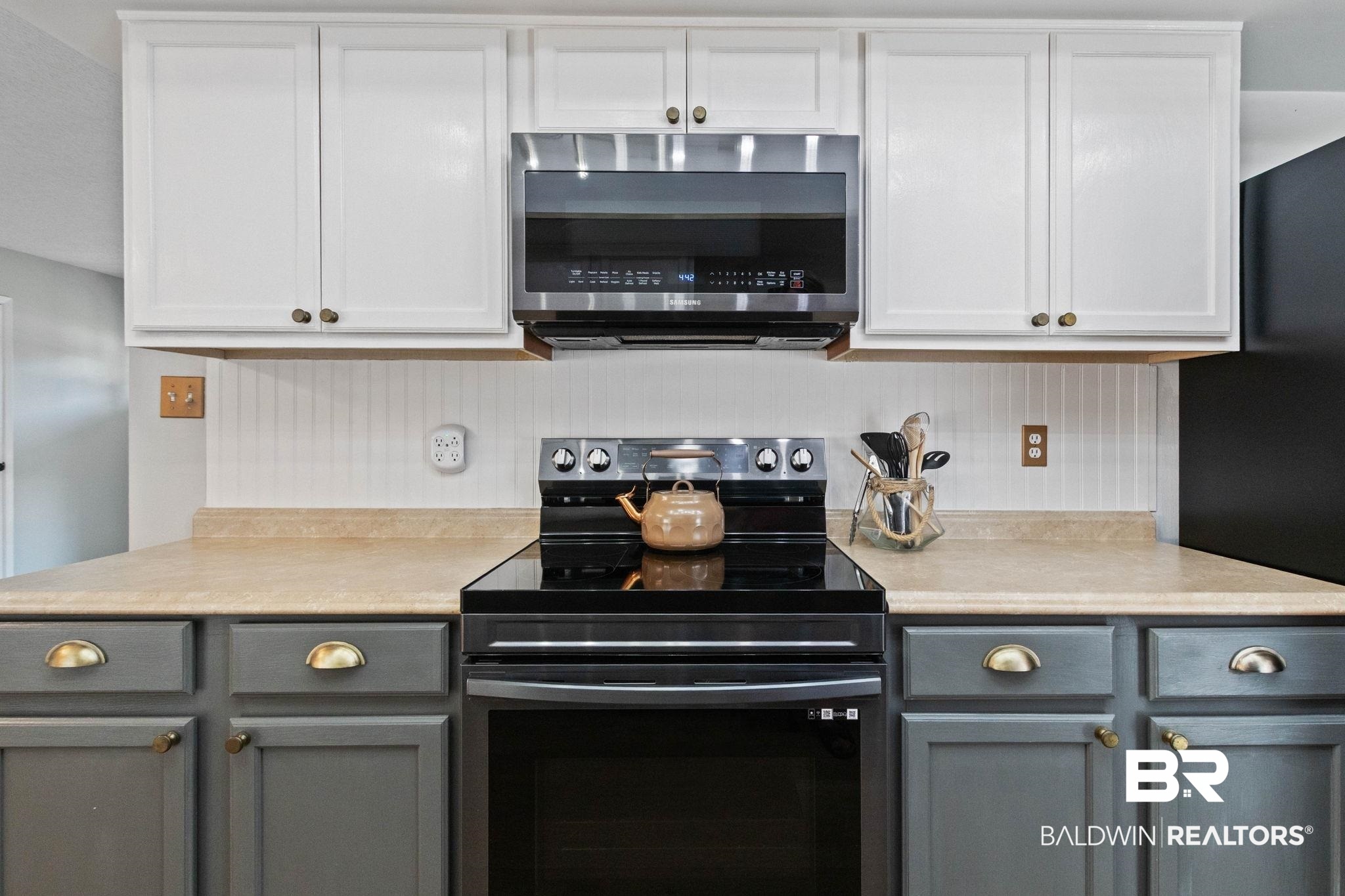 524 Ariel Avenue Foley, AL 36535 - Photo 11 of 37 Kitchen featuring two-tone cabinetry with white upper cabinets and gray lower cabinets, a light-toned countertop, a white beadboard backsplash, and a black range with an overhead stainless steel microwave