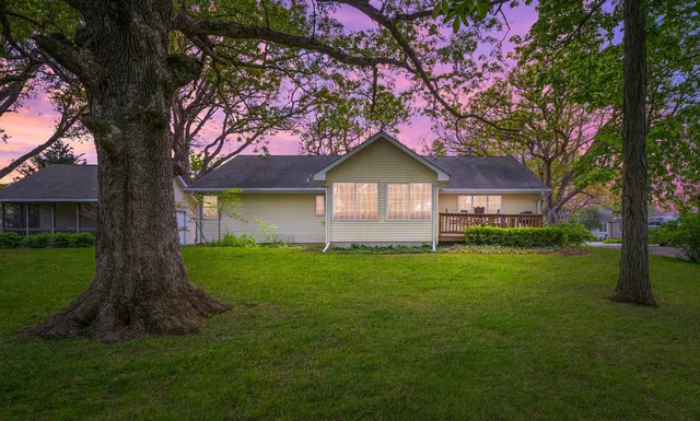 a view of a house with a big yard and large trees