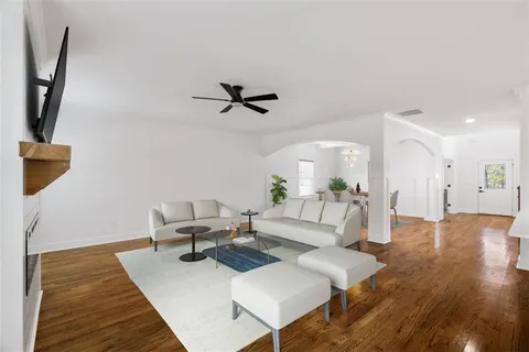 a view of an empty room with wooden floor and a ceiling fan