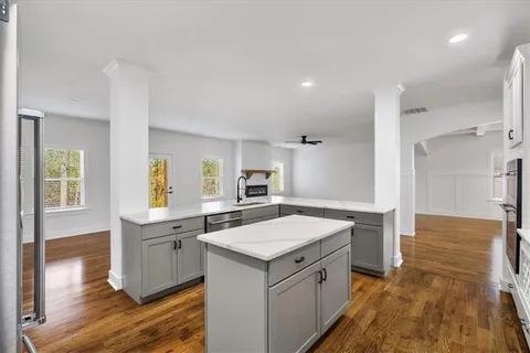 a large white kitchen with kitchen island a sink a stove and white cabinets