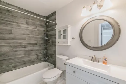 a bathroom with a toilet a sink a mirror and bathtub