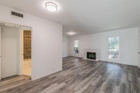 an empty room with wooden floor fireplace and windows