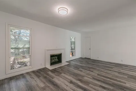 wooden floor fireplace and windows in an empty room