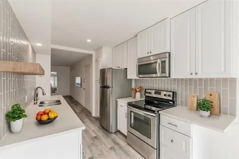 a kitchen with stainless steel appliances a stove a microwave a sink and cabinets