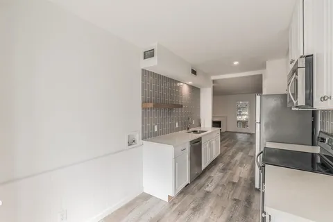 a large kitchen with a lot of counter space and wooden floor