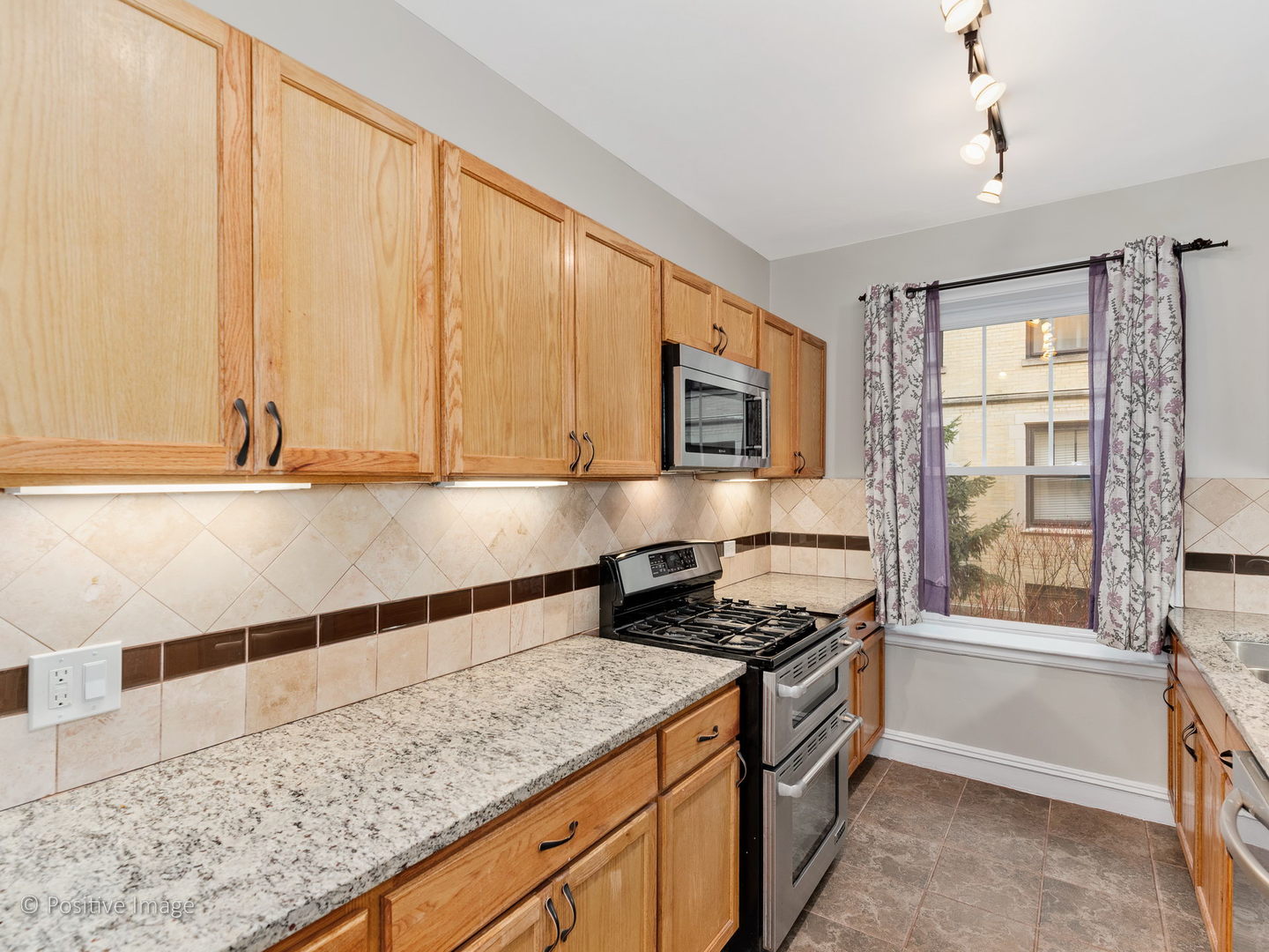 3608 North Pine Grove Avenue, Unit 1M Chicago, IL 60613 - Photo 13 of 24 a kitchen with stainless steel appliances granite countertop a stove a sink and a microwave