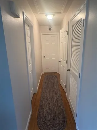 a view of a hallway with wooden floor and closet area