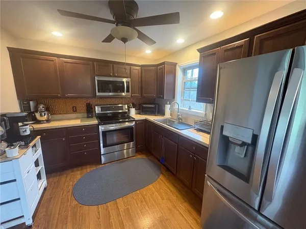 a kitchen with stainless steel appliances granite countertop a refrigerator a stove a sink and a microwave
