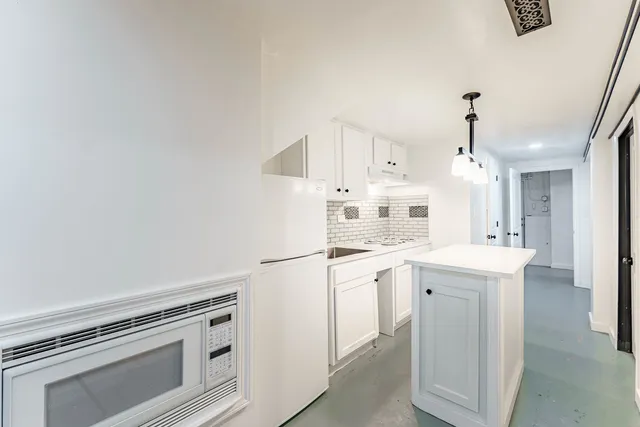 a kitchen with kitchen island a white cabinets and white appliances