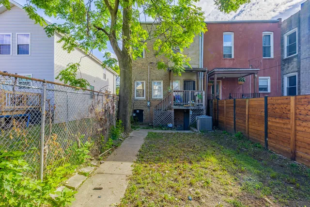a view of a brick house with many windows plants and large trees