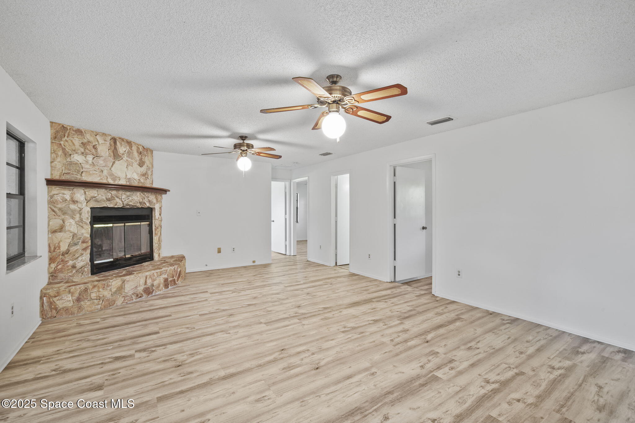 3125 Lionel Road Mims, FL 32754 - Photo 7 of 31 a view of an empty room with a fireplace and a chandelier fan