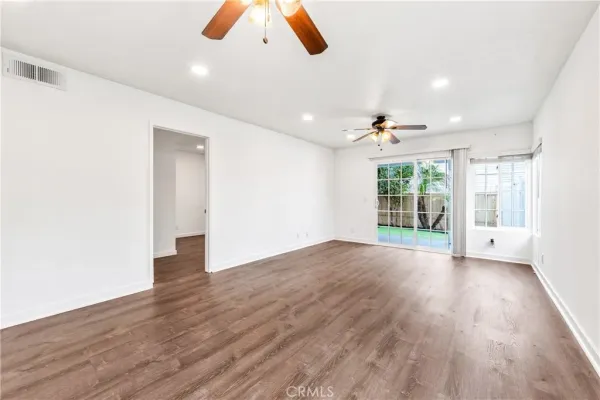 an empty room with wooden floor and windows