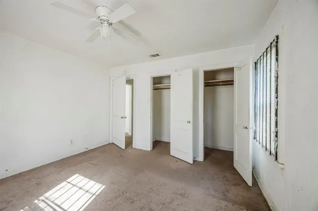 a view of empty room with windows and ceiling fan