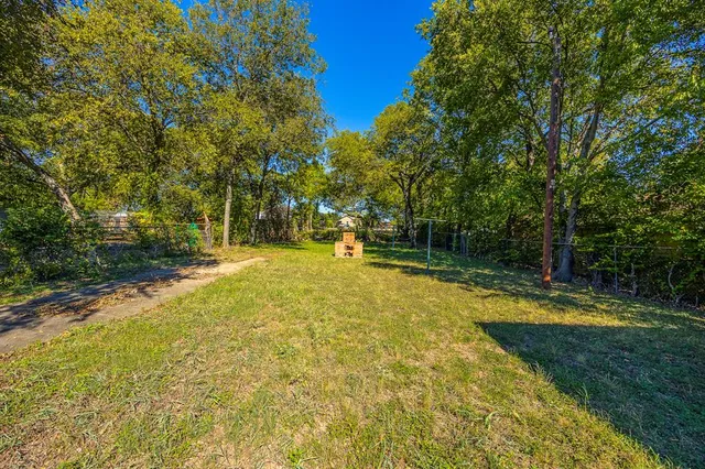 a view of a swimming pool with a yard and large trees