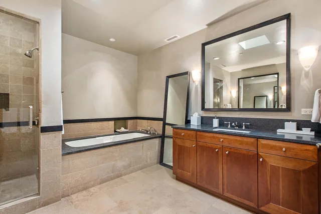 a bathroom with a bathtub a double vanity sink and mirror