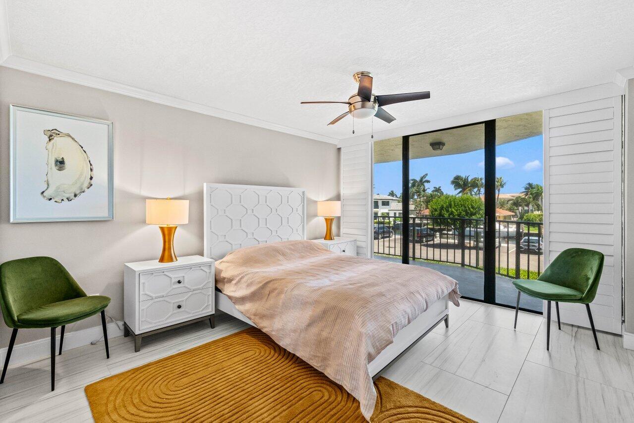 899 Jeffery Street, Unit 2120 Boca Raton, FL 33487 - Photo 18 of 38 a bedroom with a bed a chandelier and a chair