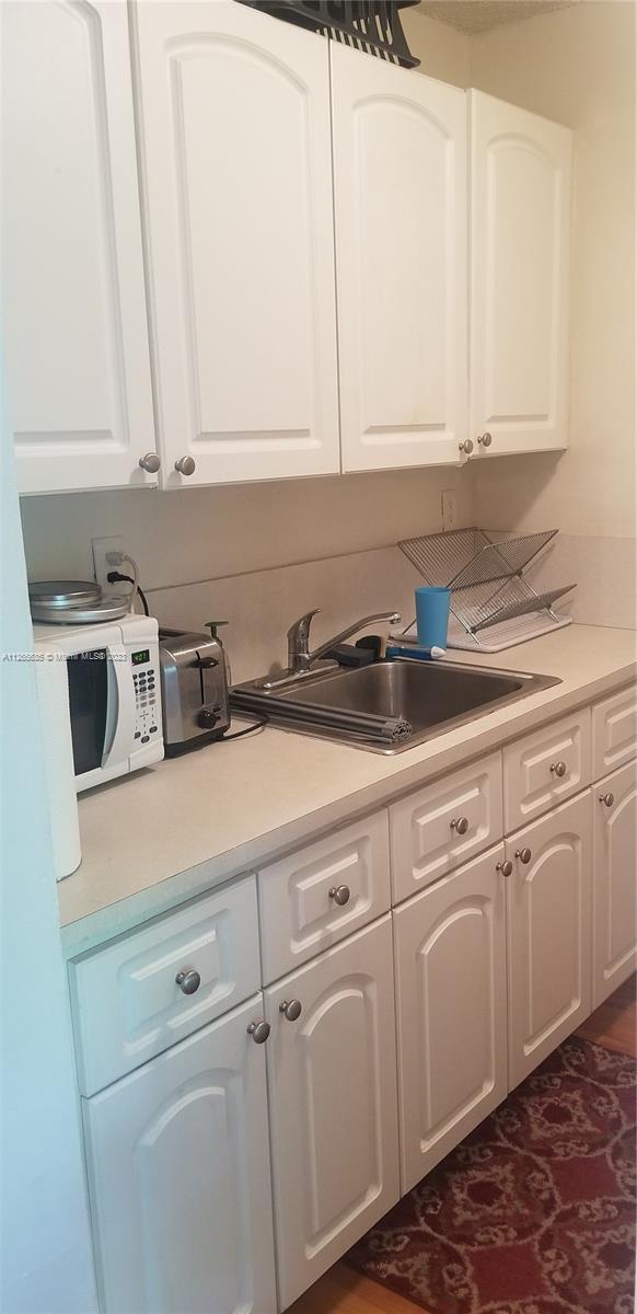 2920 Southwest 28th Terrace, Unit 304 Miami, FL 33133 - Photo 10 of 26 a kitchen with white cabinets and white appliances