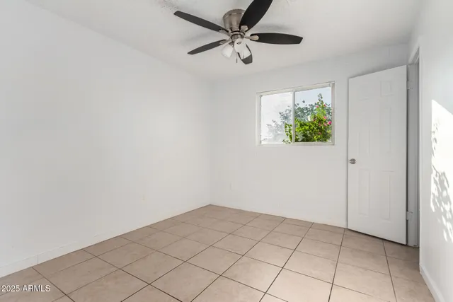 an empty room with windows and ceiling fan