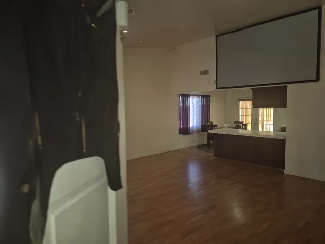 a view of an empty room with a window and wooden floor