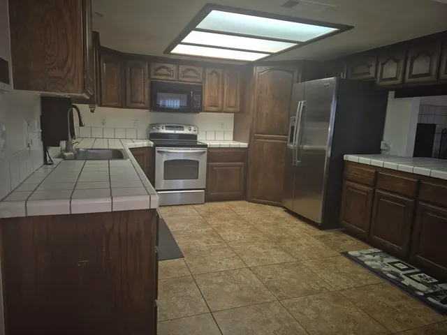 a kitchen with granite countertop a refrigerator and a stove top oven