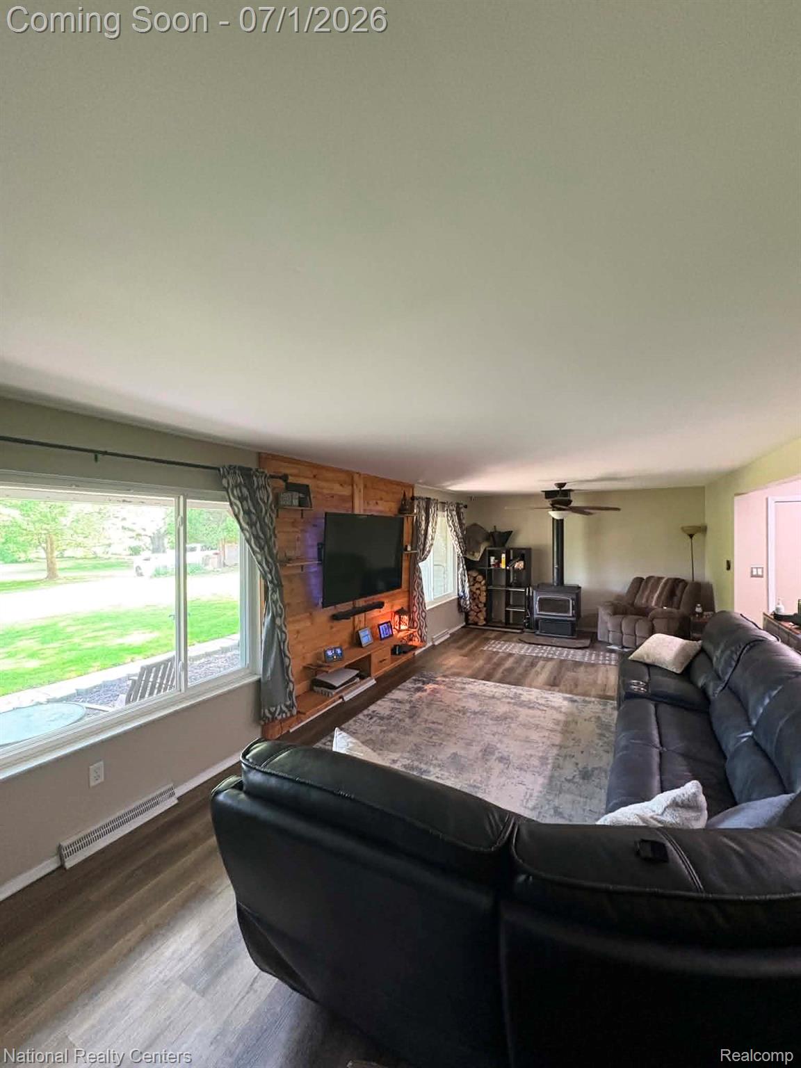 1330 Brauer Road Oxford, MI 48371 - Photo 46 of 54 Living area featuring wood-finish flooring, a wood-paneled accent wall, and large picture windows