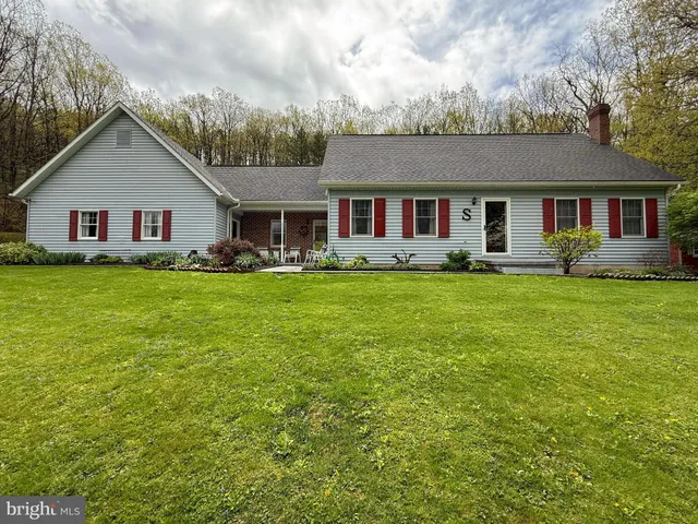 a house that is sitting in the grass with large trees
