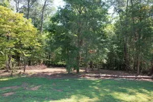 a view of a hallway with wooden floor and a bathroom