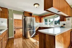 a kitchen with stainless steel appliances granite countertop a sink a refrigerator and a stove with wooden floor