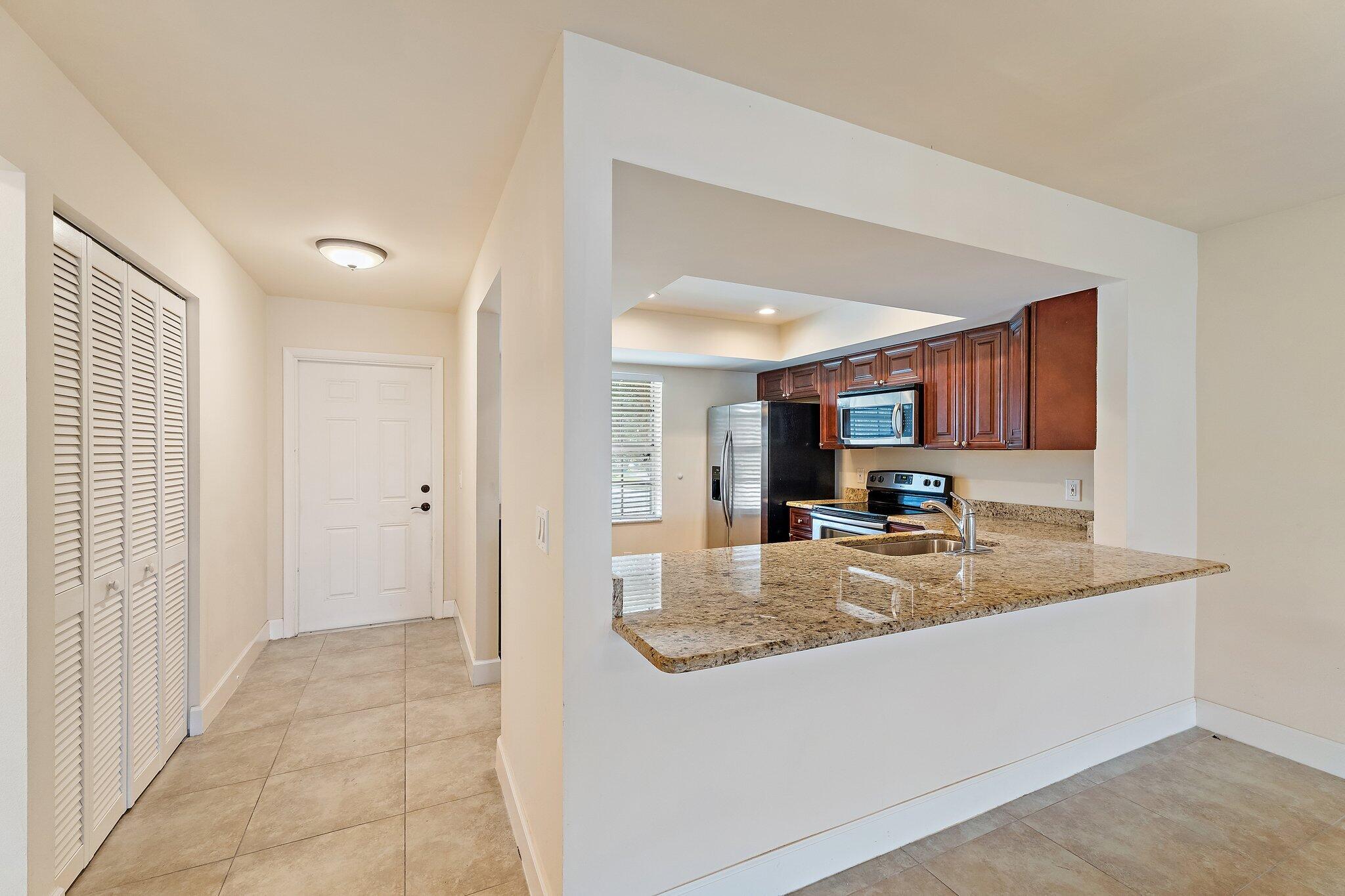 109 Doe Trail Jupiter, FL 33458 - Photo 7 of 26 a view of kitchen island a sink dishwasher a refrigerator and wooden cabinets