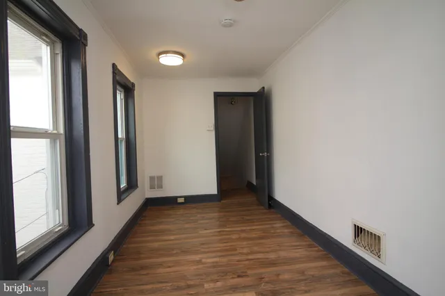 a view of hallway with window and wooden floor