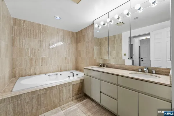 a spacious bathroom with a double vanity sink mirror and bathtub