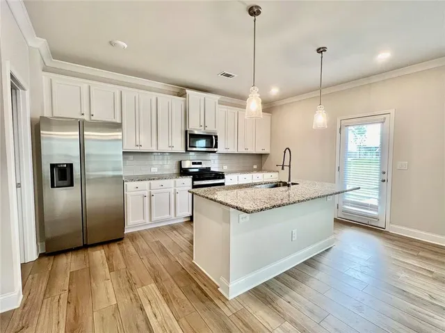 a kitchen with kitchen island granite countertop a sink a center island a refrigerator and a counter top space
