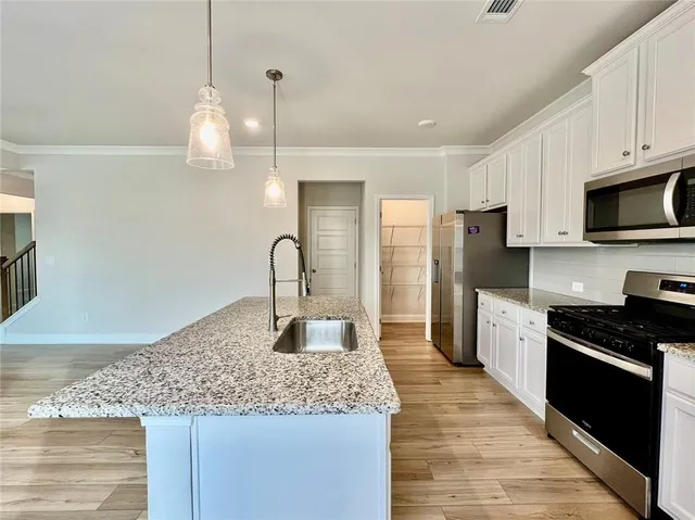 a kitchen with stainless steel appliances granite countertop a sink a stove top oven a refrigerator and dishwasher