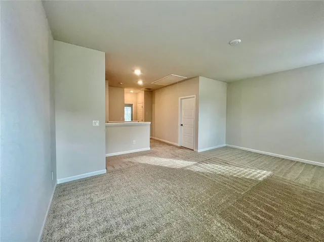 a view of an empty room and a kitchen